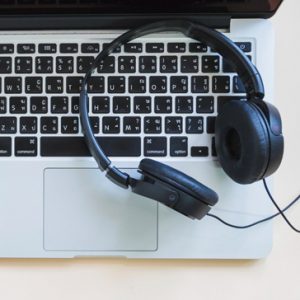 A laptop with a pair of headphones on top to demonstrate transcription services, which a Virtual Assistant can do.